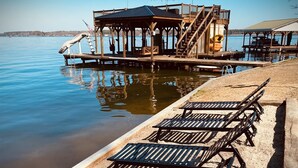 Terraza frente al agua con sillas de descanso y una estructura de madera con escalera.