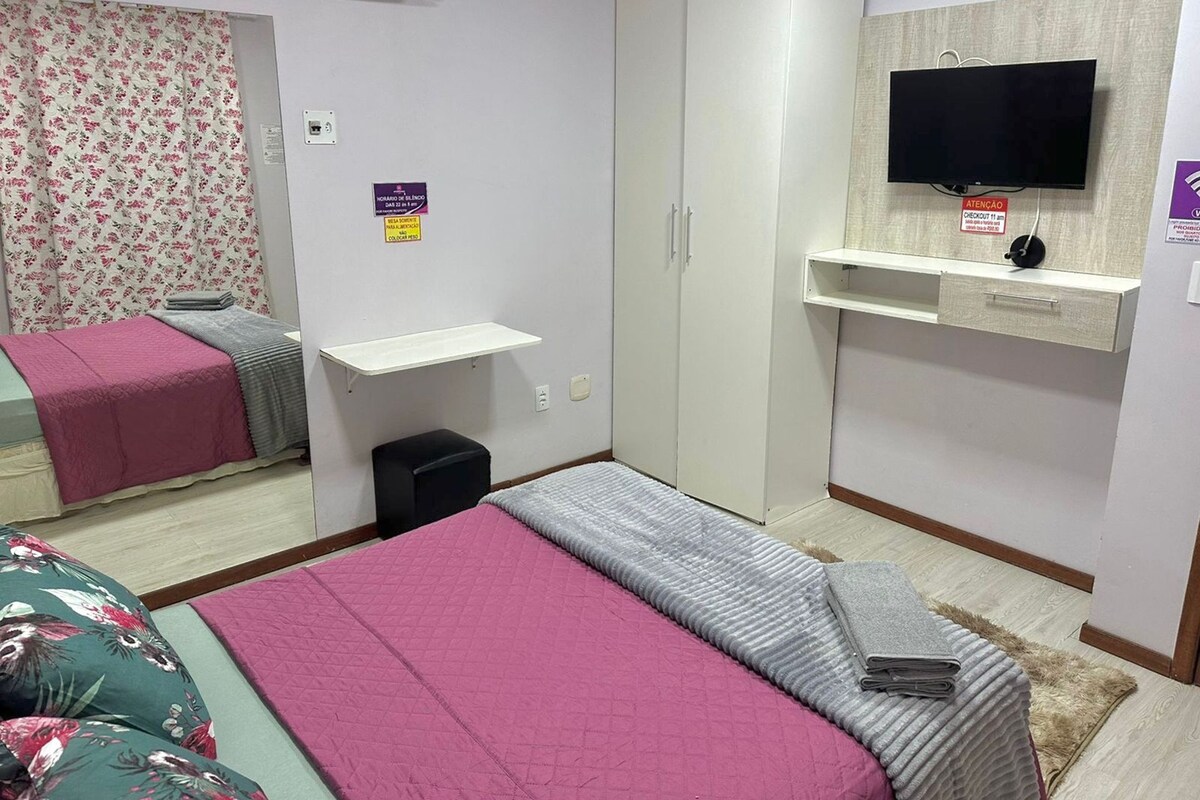 Une chambre à coucher comprenant un lit, une armoire, une télévision et un petit bureau.
