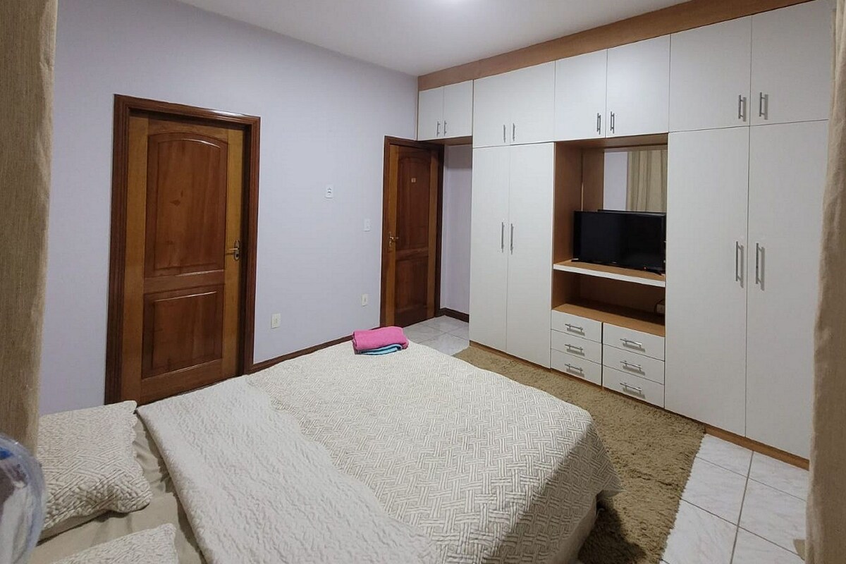 Een slaapkamer met een bed, een kledingkast en een televisie.