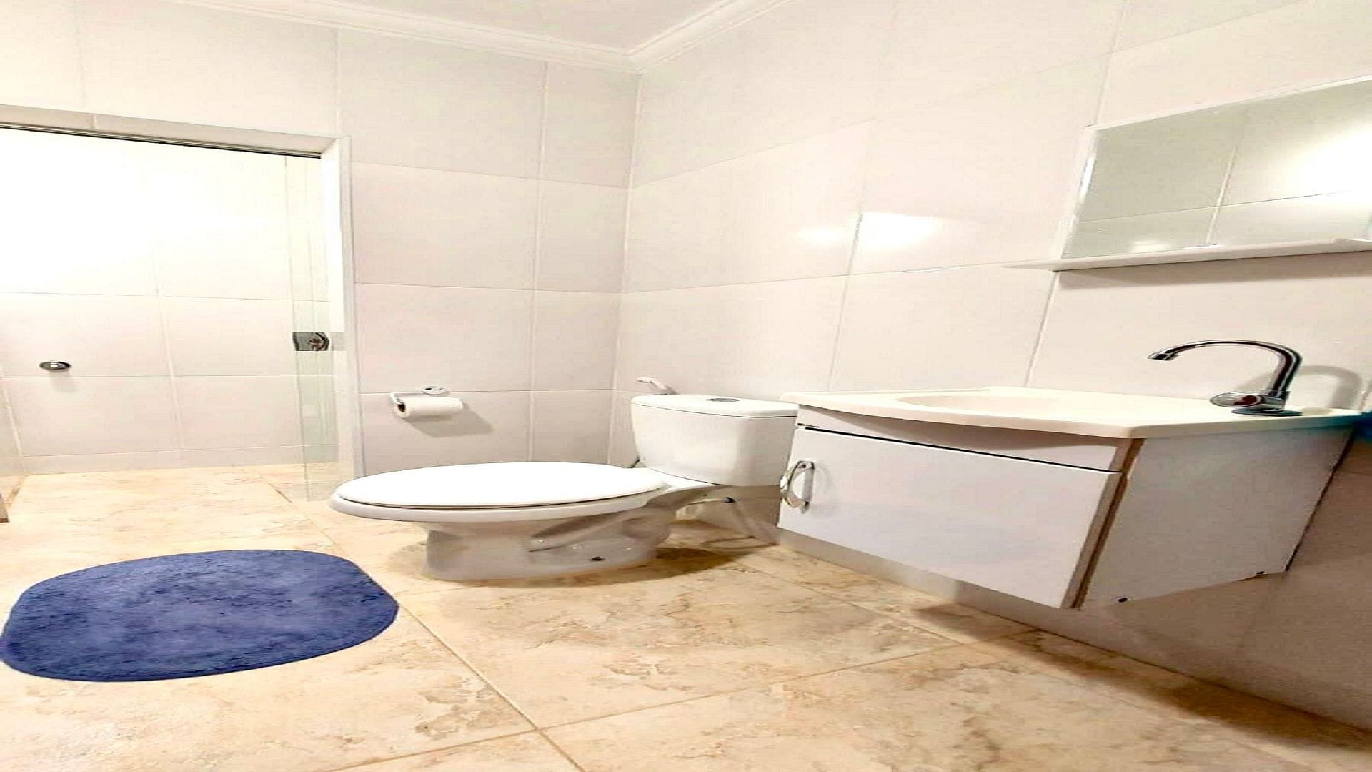 A bathroom with a toilet, sink, and mirror.