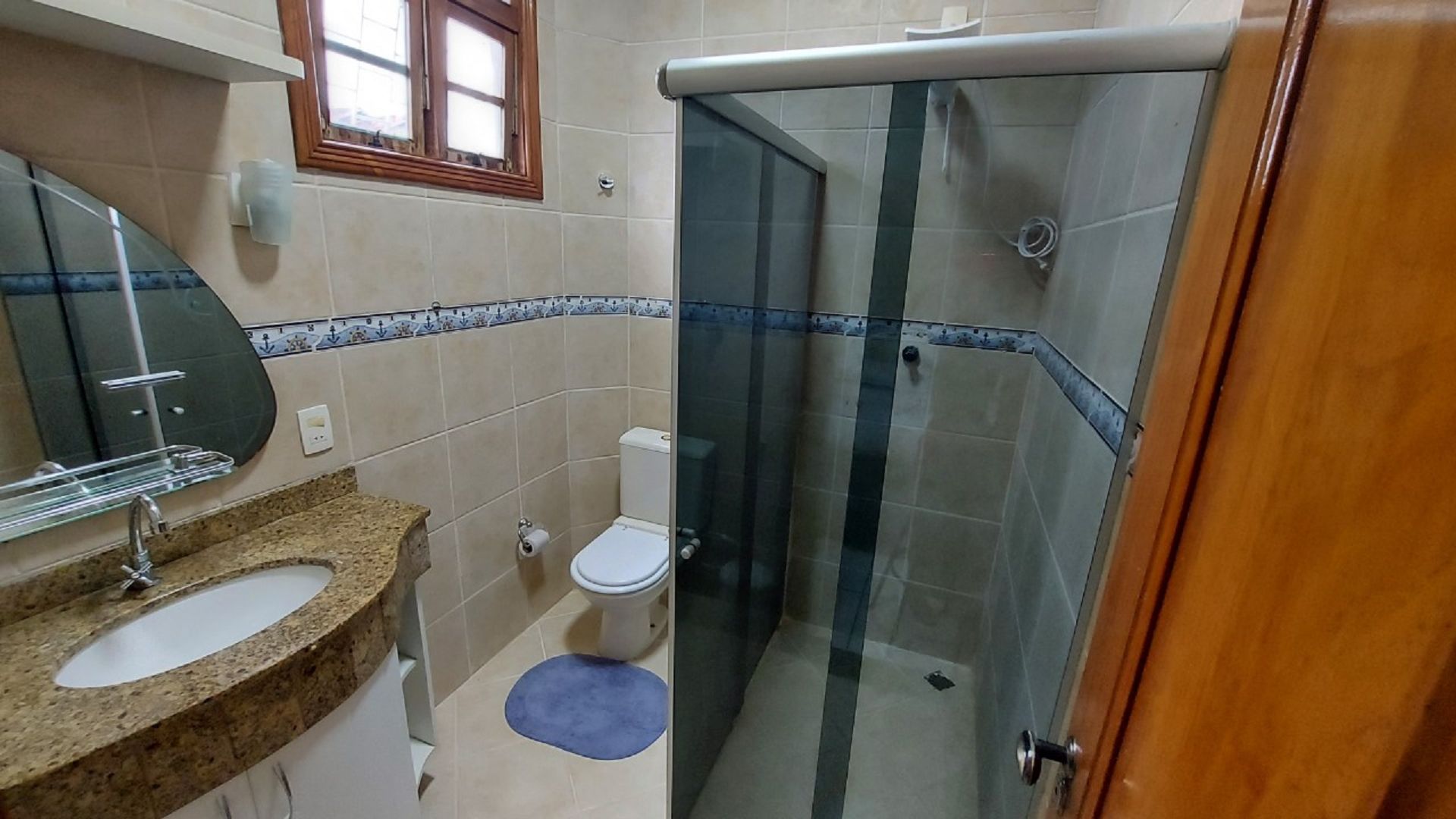 Un baño con ducha, inodoro, lavabo y espejo.