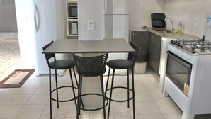 Eine Küche mit einem weißen Kühlschrank, einem Herd und zwei Barhocker.