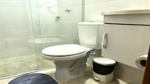 Une salle de bain équipée de toilettes, d’une douche et d’une poubelle.