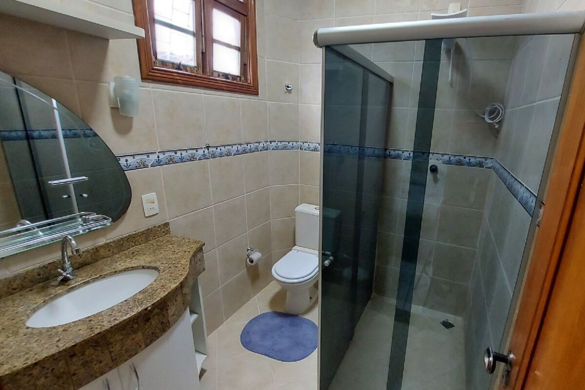 Une salle de bain équipée d’une douche, de toilettes, d’un lavabo et d’un miroir.