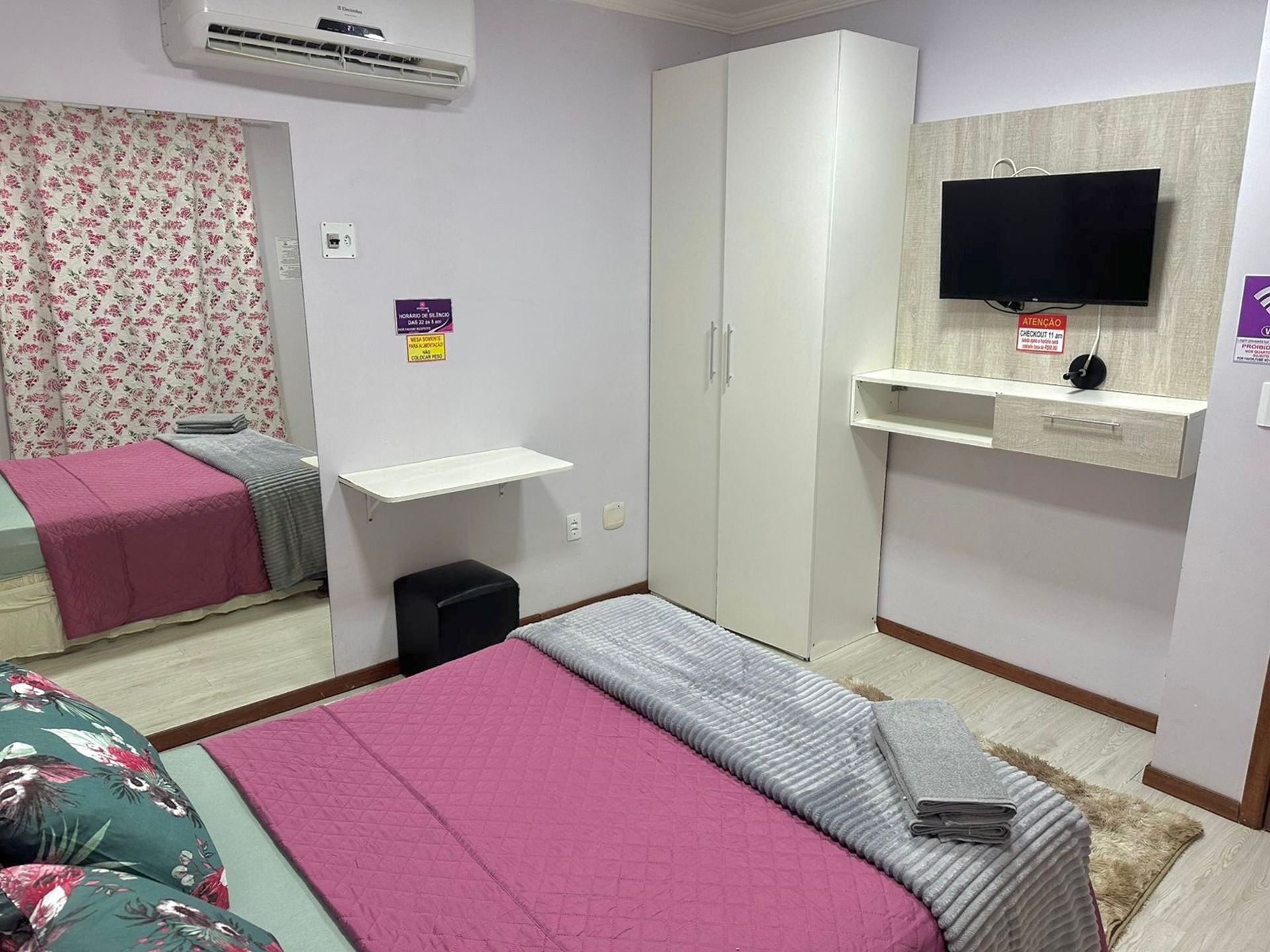 Un dormitorio con cama, armario, televisor y un pequeño escritorio.