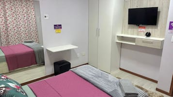 A bedroom with a bed, a wardrobe, a television, and a small desk.