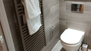 Un baño moderno con toallero integrado, inodoro y cabina de ducha de vidrio.