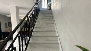 A marble staircase with black railings leading to a bright room with a large window.