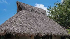 Ein Haus mit Strohdach, einer Schotterauffahrt und großen Steinen.