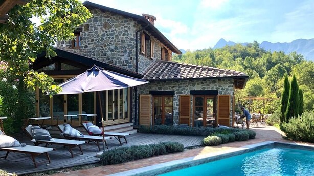 Ein Steinhhaus mit Pool, Gartenmöbeln und Bergblick.