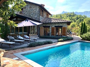 A stone house with a pool, outdoor furniture, and a view of mountains. - Luxury Tuscan Villa Hideaway in Codiponte, Italy (Codiponte)