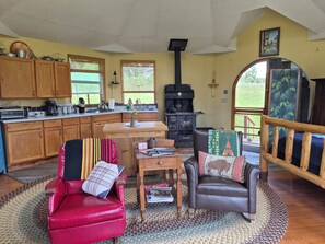 Un salon chaleureux avec une cheminée, des meubles en bois et une vue sur l’extérieur.