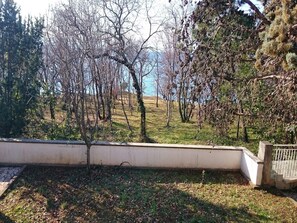 A view of a garden with trees and a body of water in the background. - Apartment Nemo - Three Bedroom Apartment with Terrace (Njivice)