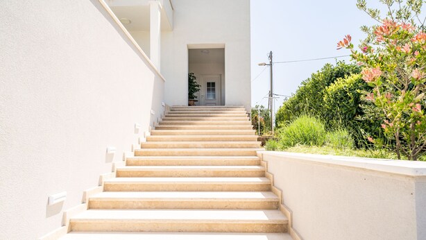 A set of beige stairs leading to a white door, surrounded by greenery and a white wall. - Apartment Doma - Two Bedroom Apartment with Terrace (Cavtat)