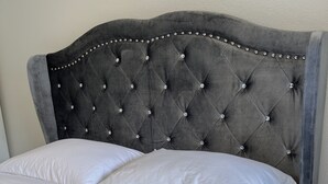 Een bed met een gestoffeerd hoofdbord en witte beddengoed.