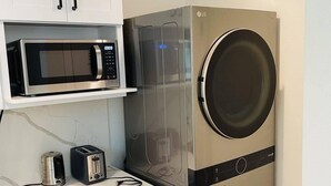 Een compacte keuken met een magnetron, broodrooster en een was-droogcombinatie met dubbele deur.