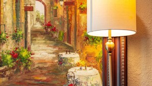 Un tableau encadré représentant une scène de rue, avec un lampadaire et un jeu de société sur une table en bois.