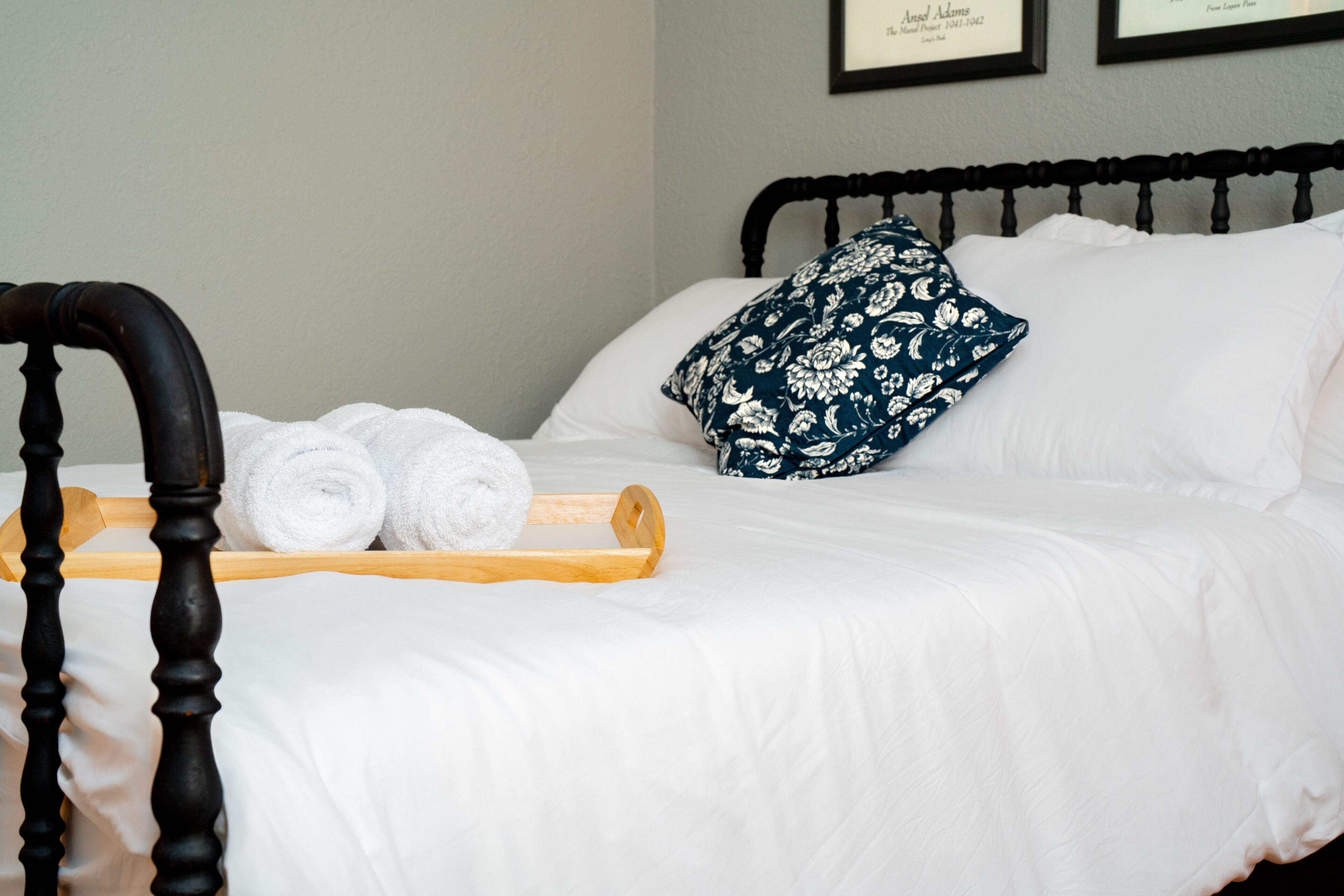 Un lit bien fait, avec des draps blancs, une tête de lit en bois et un coussin décoratif.