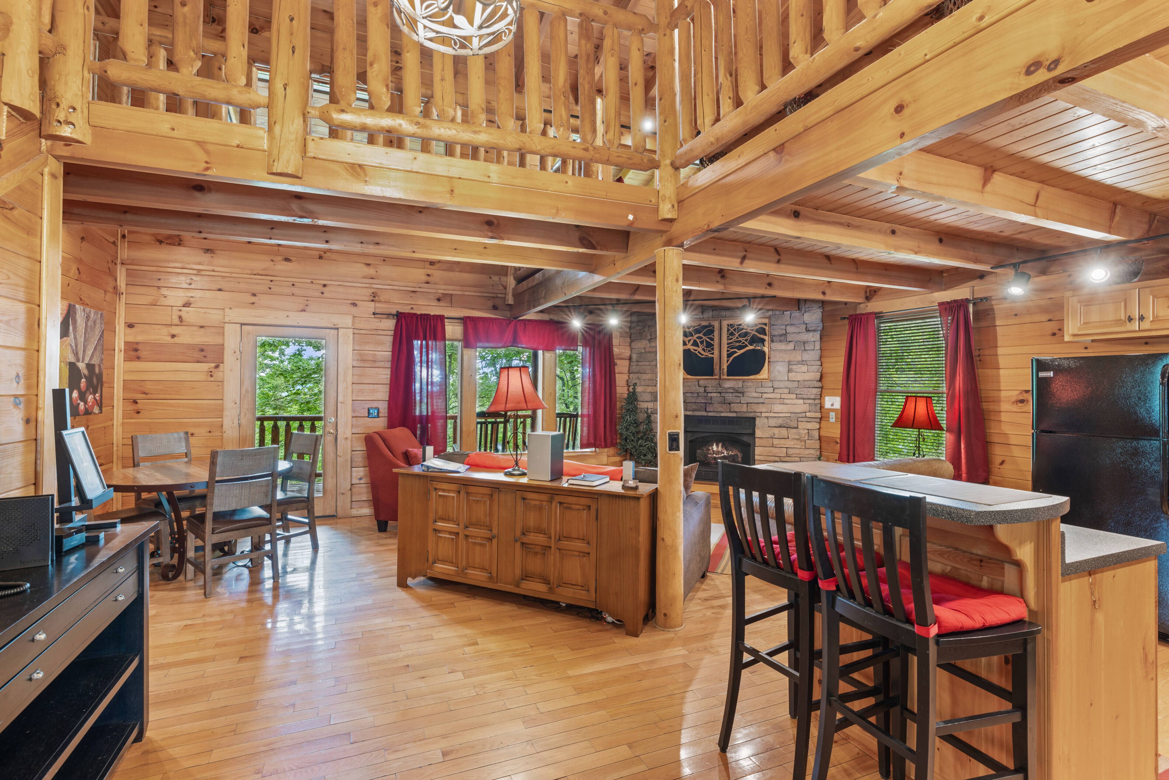 A wooden cabin interior with a dining area, kitchen, and fireplace.
