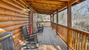 A wooden deck with rocking chairs and a wooden railing.