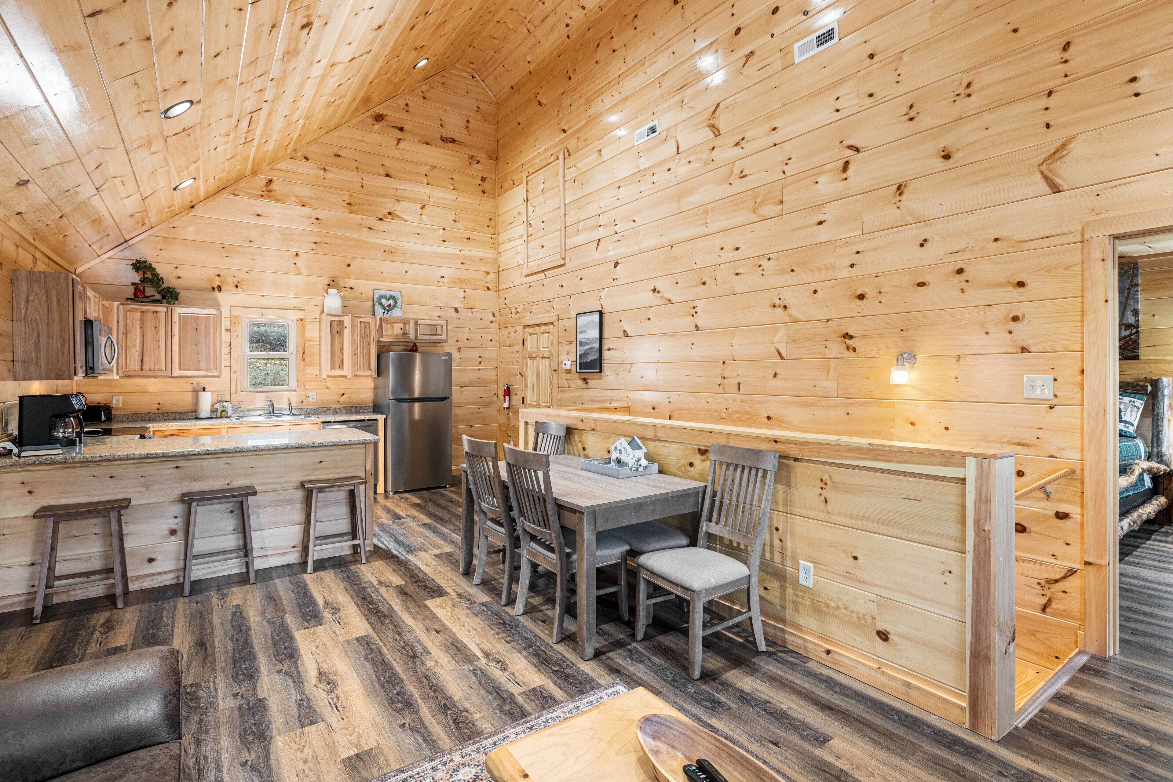 Interior de una cabaña de madera con cocina, comedor y barra.