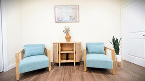 Una habitación con dos sillones azul claro, una mesita de madera con un jarrón y un cuadro en la pared.