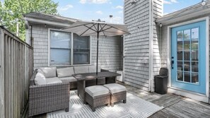Un patio con una mesa, sillas, una sombrilla y una puerta azul.