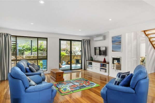 Relax in a serene space with a garden and pool view, featuring a comfortable sofa and flat-screen TV.