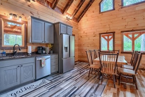 A wooden interior with a kitchen, dining area, and large windows.
