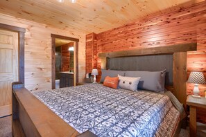 A wooden cabin bedroom with a bed, nightstands, and a mirror.