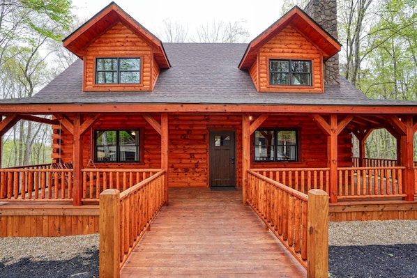 Une cabane en rondins avec une entrée centrale, deux vérandas latérales et une allée couverte.