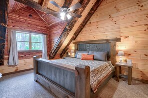 A bedroom with a wooden ceiling, a bed, a nightstand, and a window. - Jackson's Luxury Hideaway - Sleeps 8 - Hocking (Logan)