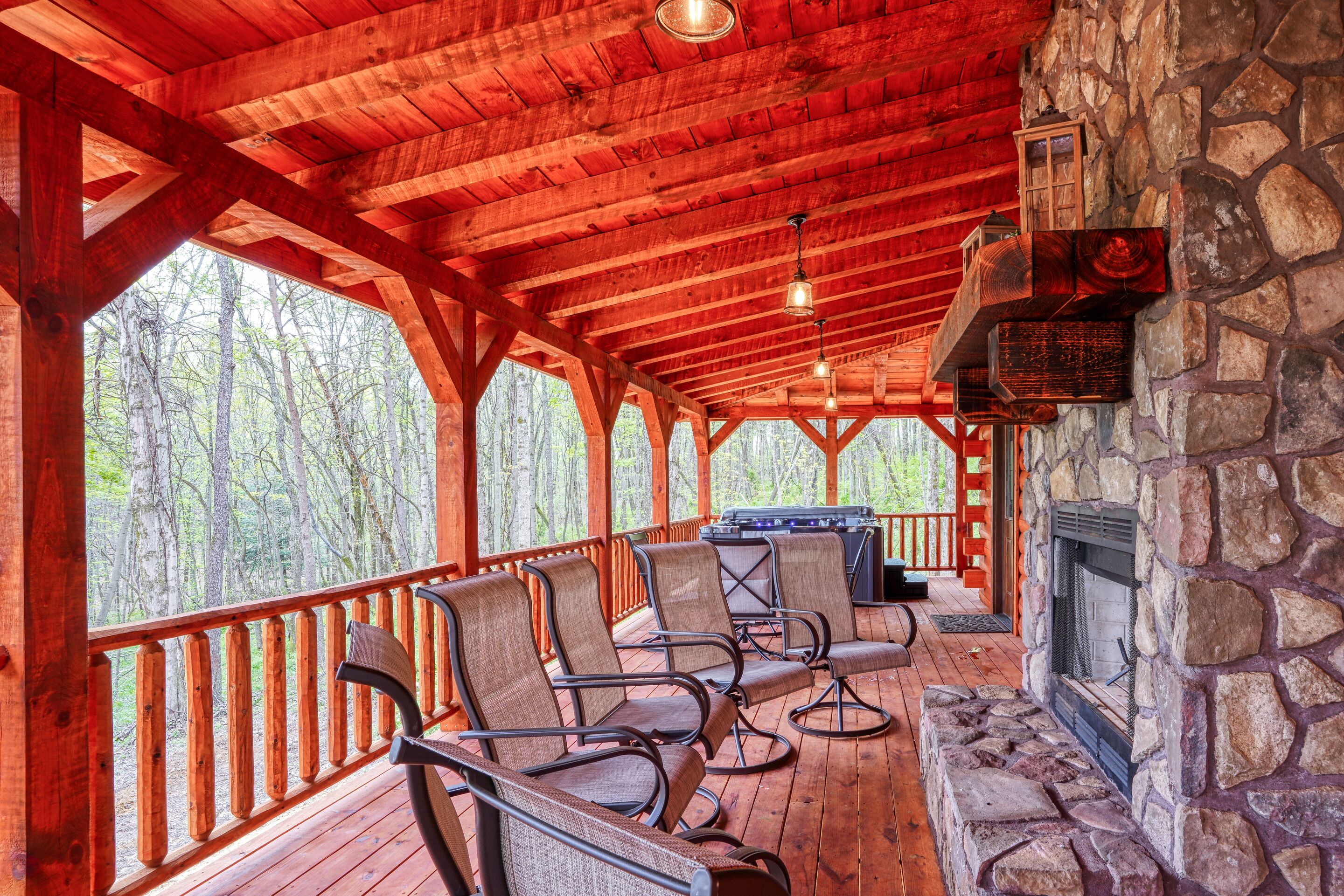 A covered outdoor seating area with wooden chairs and a stone fireplace.