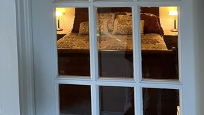 A room with a bed, two bedside tables with lamps, and a wall-mounted ship's wheel decoration.
