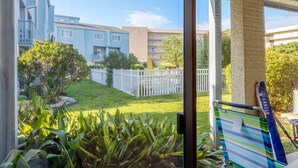 A view of a residential building with a fenced yard, a pool, and a chair.