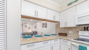 A modern kitchen with white cabinets, a granite countertop, and a built-in microwave.