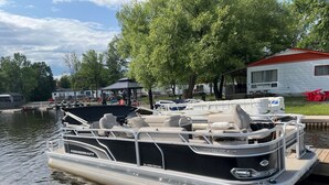 Un pontó amarrat en una marina, amb una zona de seients coberta i una cabina.