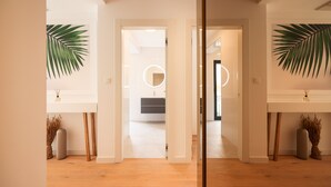 A modern interior with a wooden floor, white walls, and a visible bathroom with a circular light fixture. - Adria Concept boutique apartments (Zadar)