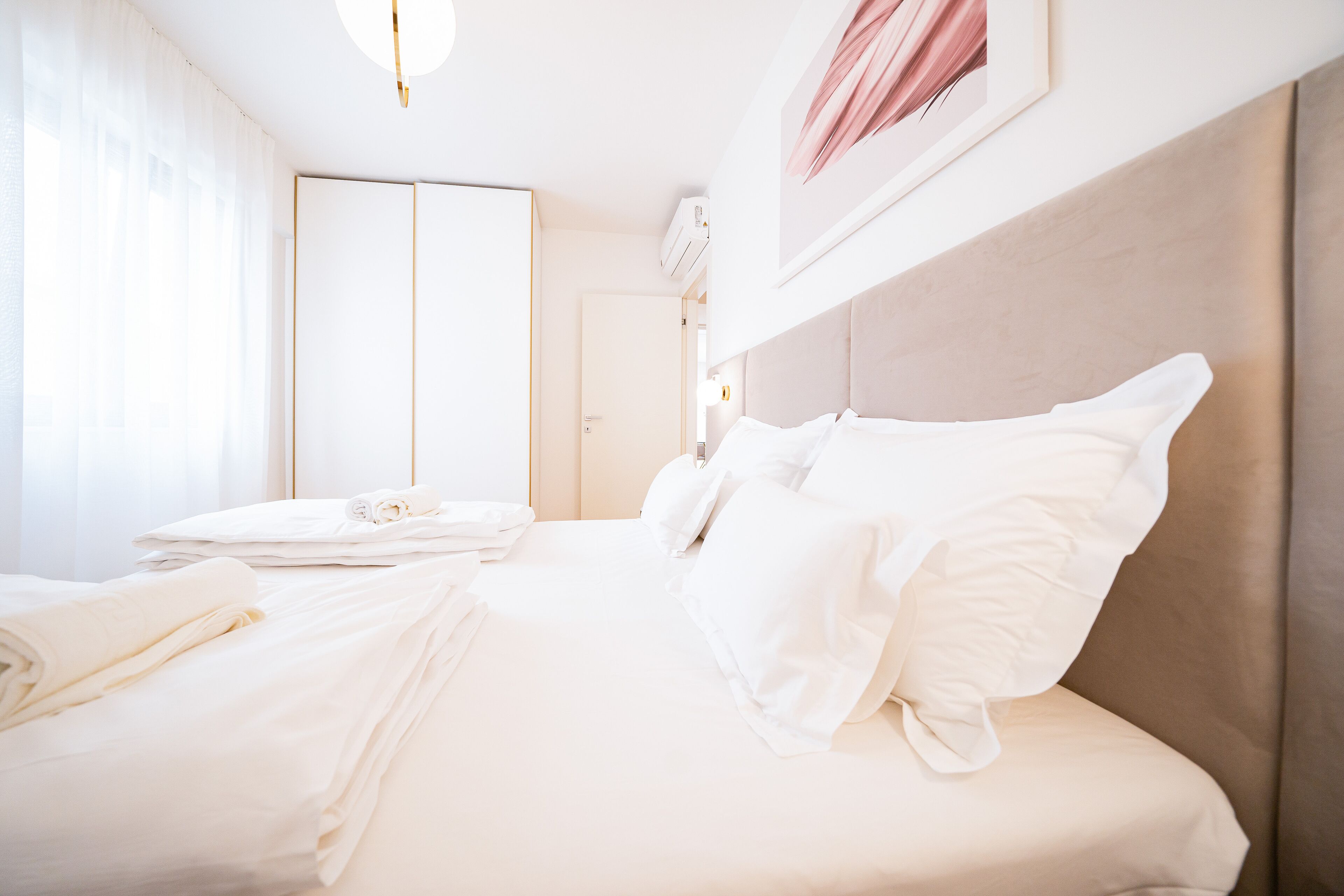 Ett hotellrum med en snyggt bäddad säng, en garderob och ett inramat konstverk på väggen.
