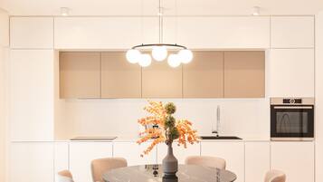 A modern kitchen with white cabinetry, a round dining table, six chairs, and a central island.