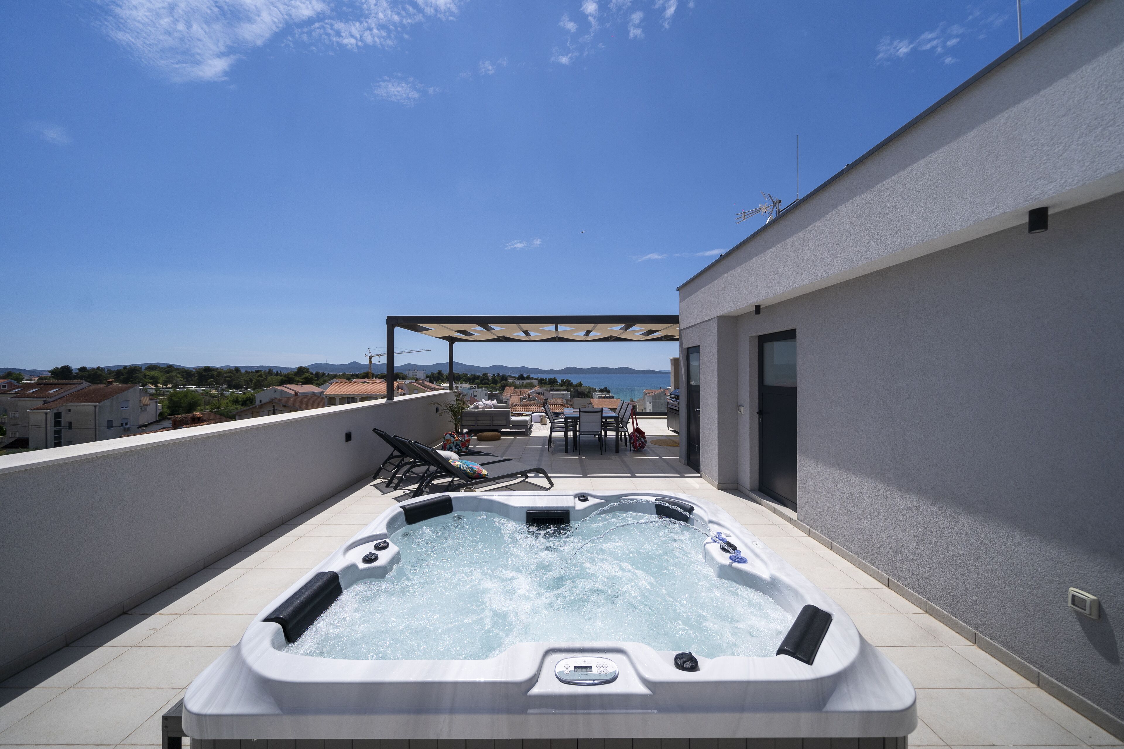 Una terraza en la azotea con jacuzzi, mobiliario exterior y vistas a la ciudad.