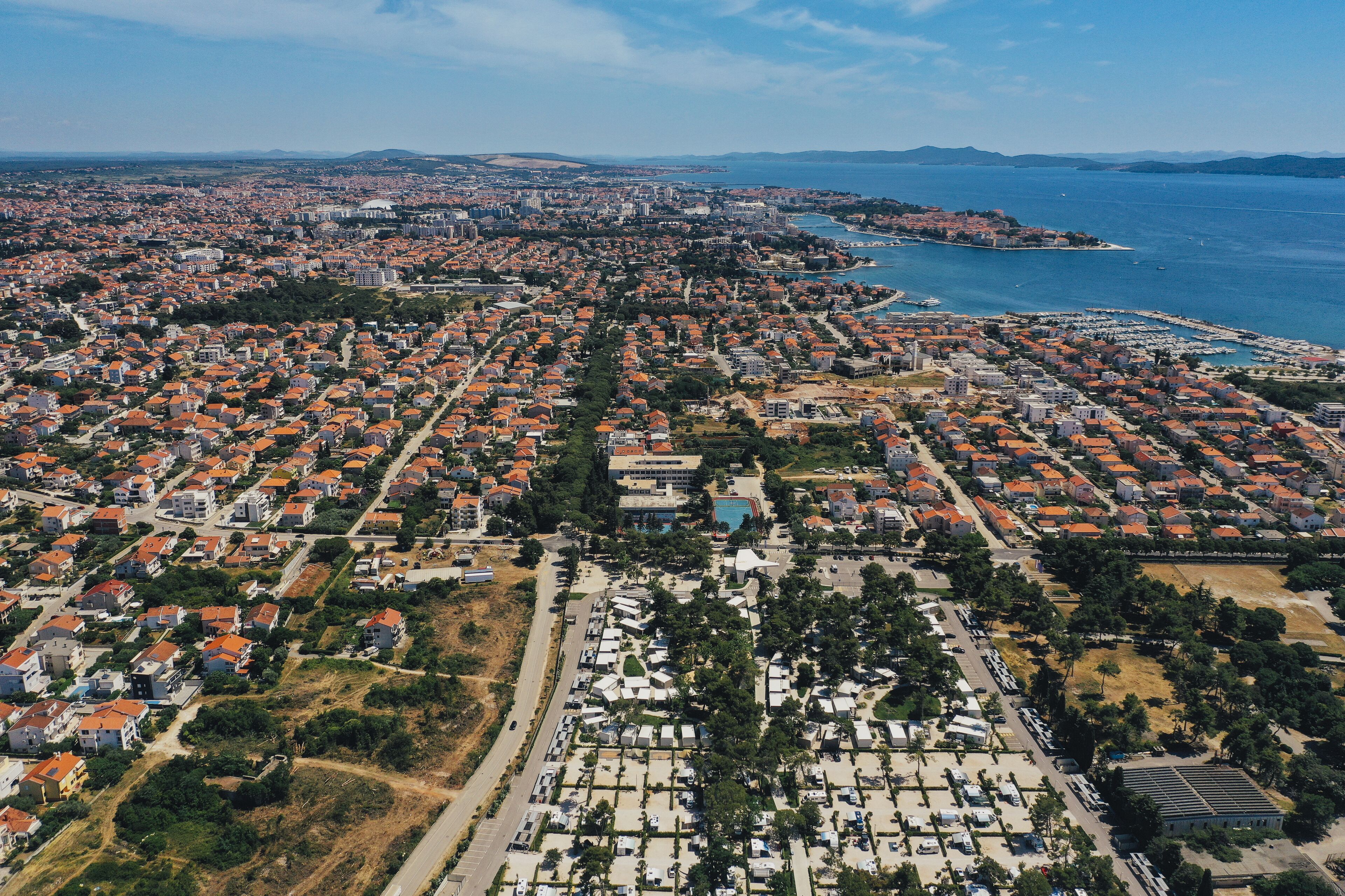 An aerial view of a coastal city with residential areas, a marina, and a large body of water.