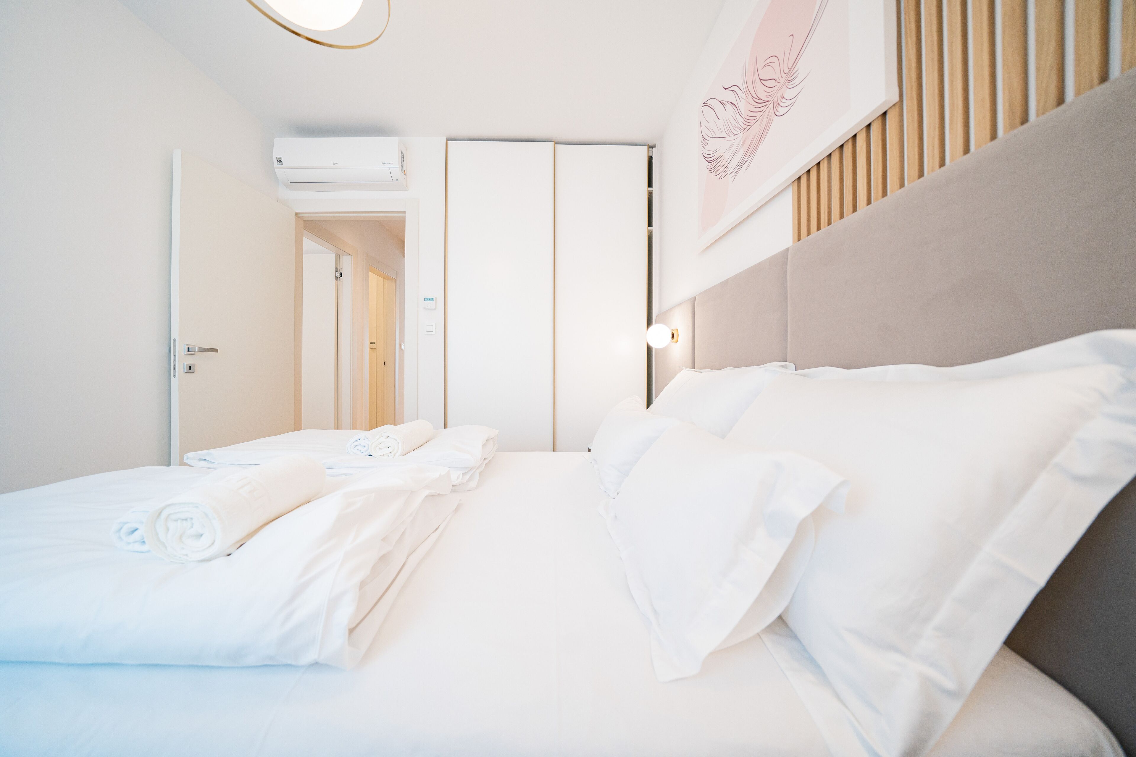 A hotel room with a bed, a wardrobe, a mirror, and a wall-mounted air conditioner.