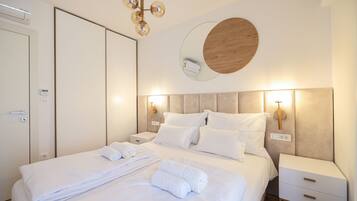 A modern hotel room with a neatly made bed, a bedside table with a lamp, and a wall-mounted mirror.