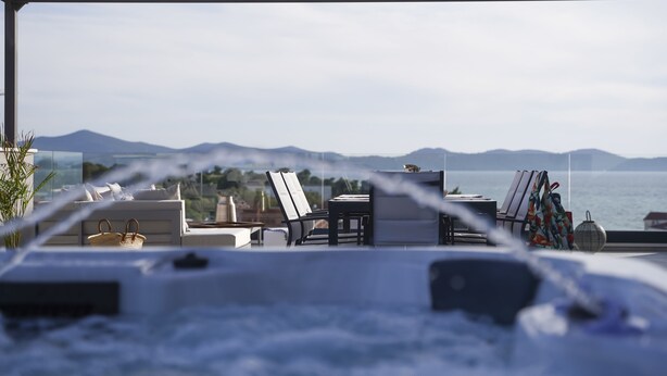 A spa area with a hot tub, lounge chairs, and a view of the sea and mountains. - Adria Concept boutique apartments (Zadar)