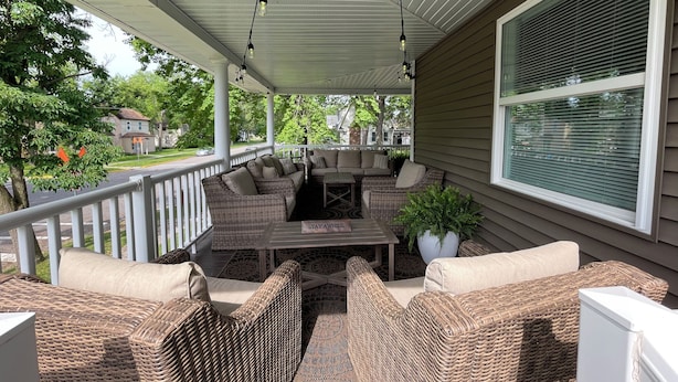 Een overdekt terras met rieten meubels, een tafel en hanglampen.