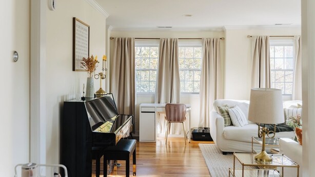 Ett vardagsrum med ett piano, en vit soffa, ett soffbord och en lampa.