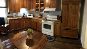 Une cuisine avec des meubles de rangement en bois, une cuisinière, un four à micro-ondes et un évier.