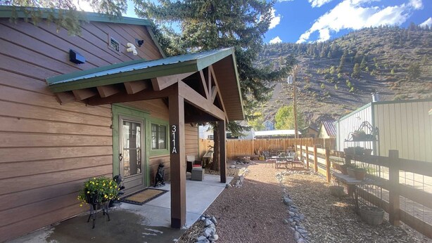 Une cabane en bois dotée d’un porche couvert, d’une allée en gravier et d’une cour clôturée.
