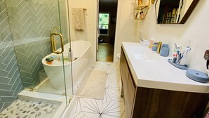 A modern bathroom with a freestanding bathtub, a glass shower enclosure, and a vanity with a sink and mirror. - Family friendly home on quiet street (Atlanta)